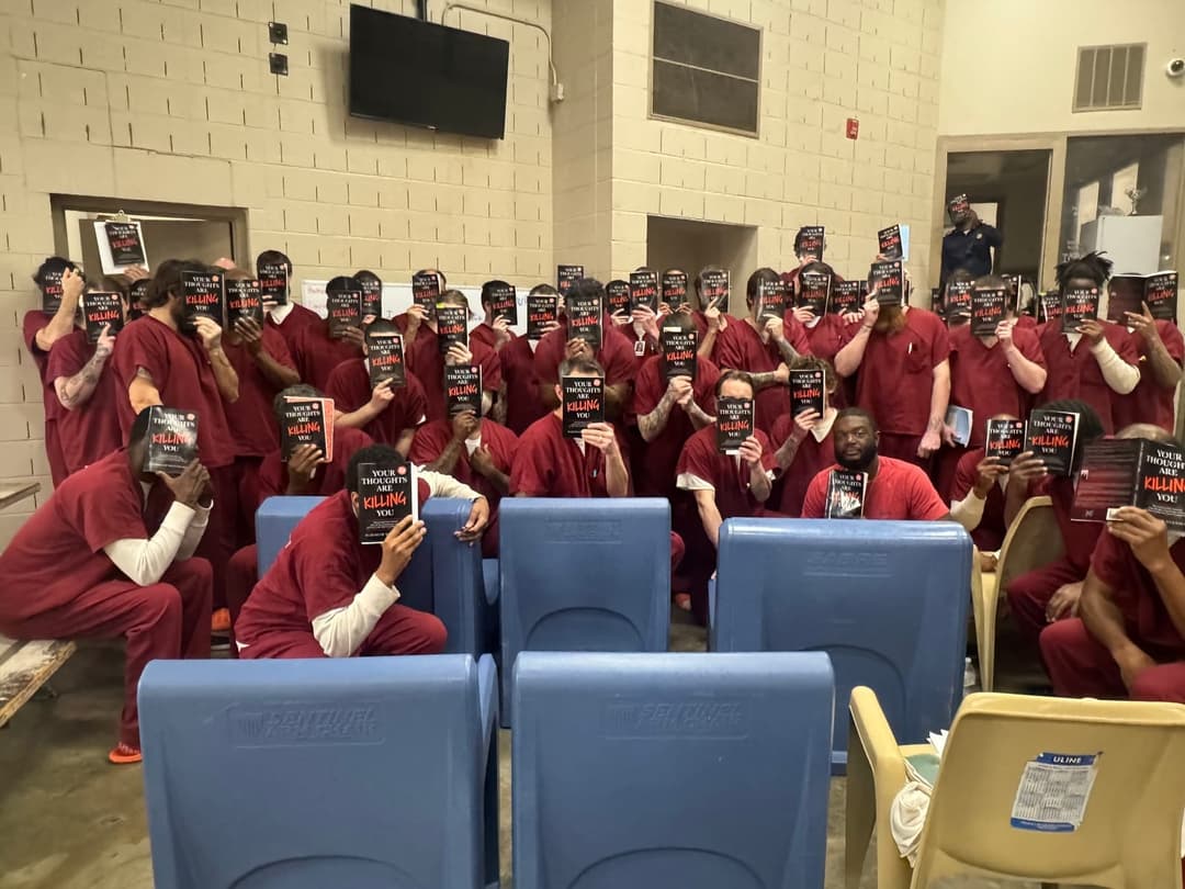 Inmates holding copies of Your Thoughts Are Killing You